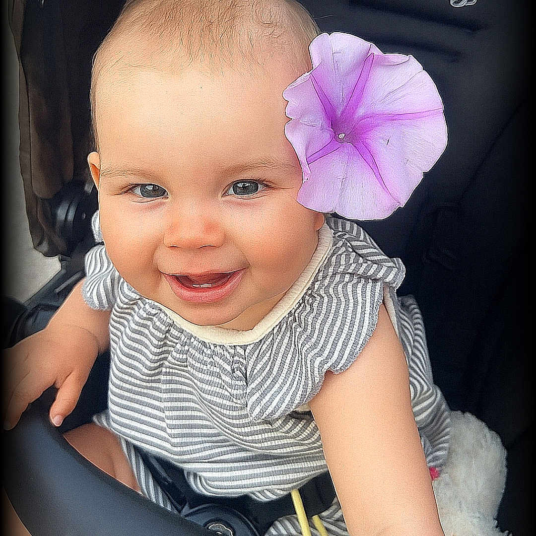 ézia participe au concours pour gagner de l'argent avec cette photo : baby, baby_clothes, child, closeup, cute, face, flower, flower_accessory, happy, head, infant, outdoor, person, portrait, seat, skin, smile, striped_clothing, stroller, young_child