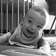 Leon a rejoint le concours — aidez-le/la à gagner de superbes lots ! baby, smiling, face, infant, bib, striped_shirt, crib, indoor, black_and_white, happy, child, young, cute, portrait, crawling, floor, head, person, expression, home