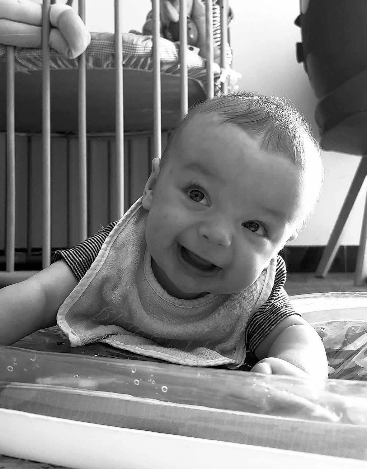 Leon a rejoint le concours — aidez-le/la à gagner de superbes lots ! baby, smiling, face, infant, bib, striped_shirt, crib, indoor, black_and_white, happy, child, young, cute, portrait, crawling, floor, head, person, expression, home
