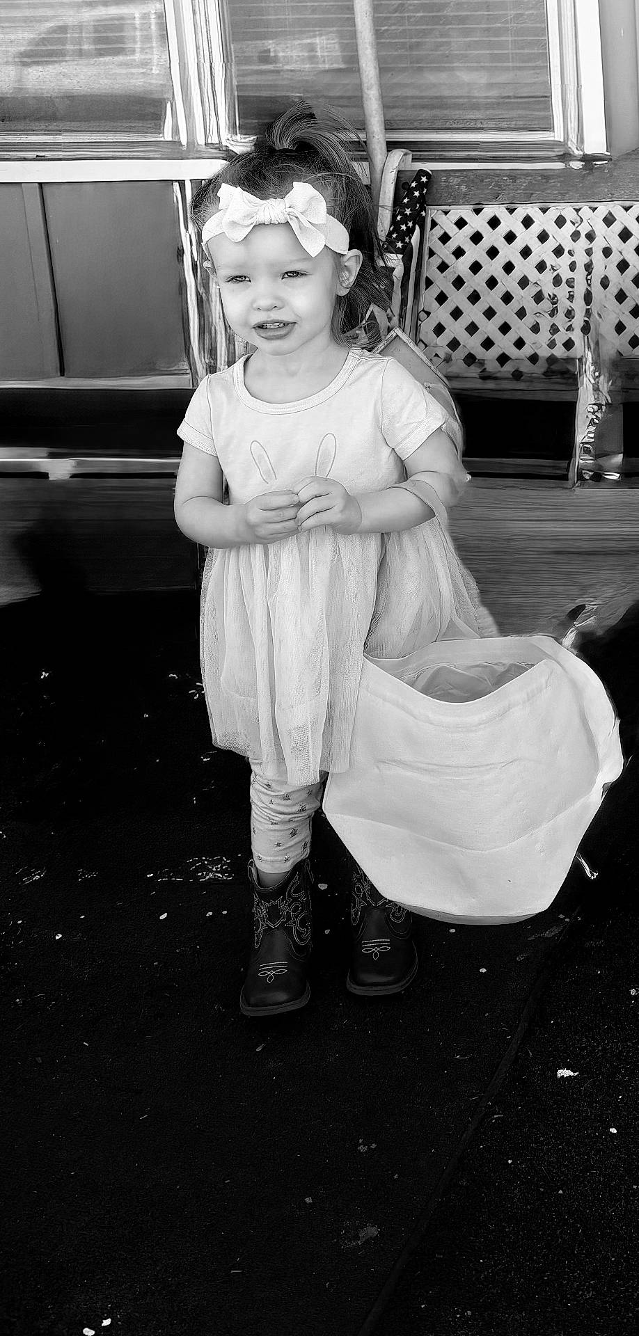 Tegan is registered to the contest to win money with this photo: background, bag, black_and_white, boots, bow, child, clothing, dress, footwear, girl, happy, headband, outdoor, person, playful, portrait, smile, standing, window, young_child