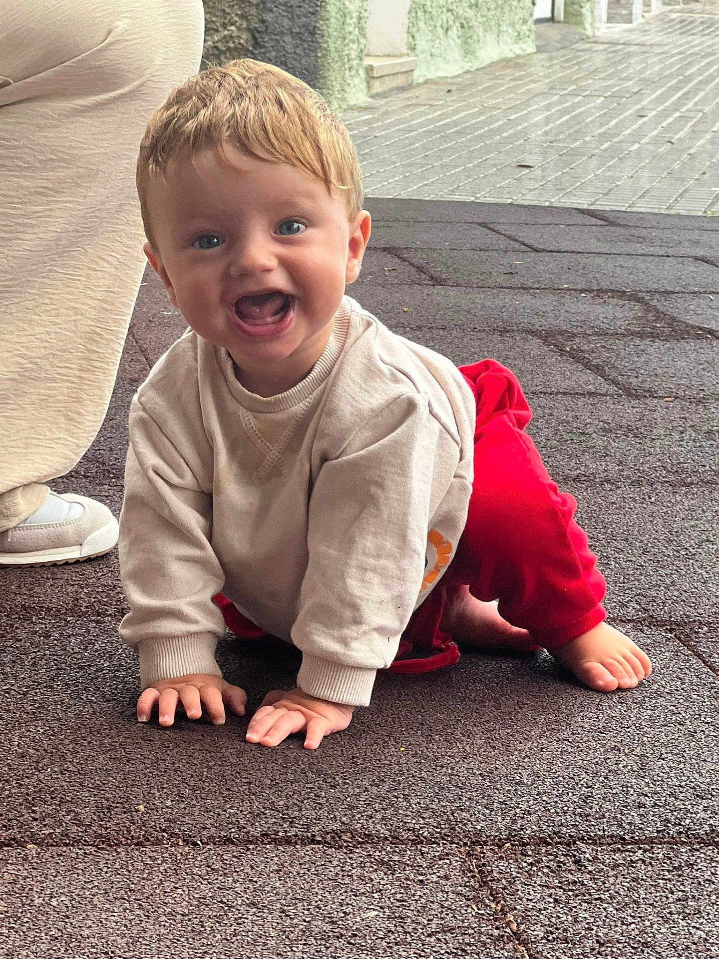 Julen joined the competition — help win amazing prizes! toddler, child, smiling, crawling, outdoor, beige_sweater, red_pants, happy, baby, footwear, shoe, person, face, blue_eyes, short_hair, pavement, texture, natural_light, casual_clothing, joyful
