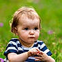 Mathilde a rejoint le concours — aidez-le/la à gagner de superbes lots ! toddler, child, flower, grass, outdoor, nature, striped_shirt, necklace, curly_hair, greenery, field, purple_flowers, person, portrait, young_child, summer, daylight, cute, innocent, closeup