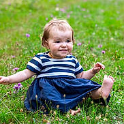 Mathilde a rejoint le concours — aidez-le/la à gagner de superbes lots ! toddler, child, smile, grass, flowers, outdoor, nature, dress, barefoot, greenery, happy, playful, baby, young_child, summer, field, person, cute, sitting, portrait