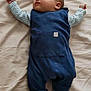 baby, infant, blue_romper, gray_socks, lying_down, bed, blanket, cute, child, small_hands, small_feet, sleepwear, indoors, portrait, cozy, soft_lighting, resting, young, adorable, peaceful
