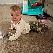 Parker is registered to the contest to win money with this photo: baby, child, infant, crawling, sitting, face, portrait, curious, indoor, home, carpet, toy, pacifier, camouflage, clothing, long_sleeves, playmat, flip_flops, couch, living_room