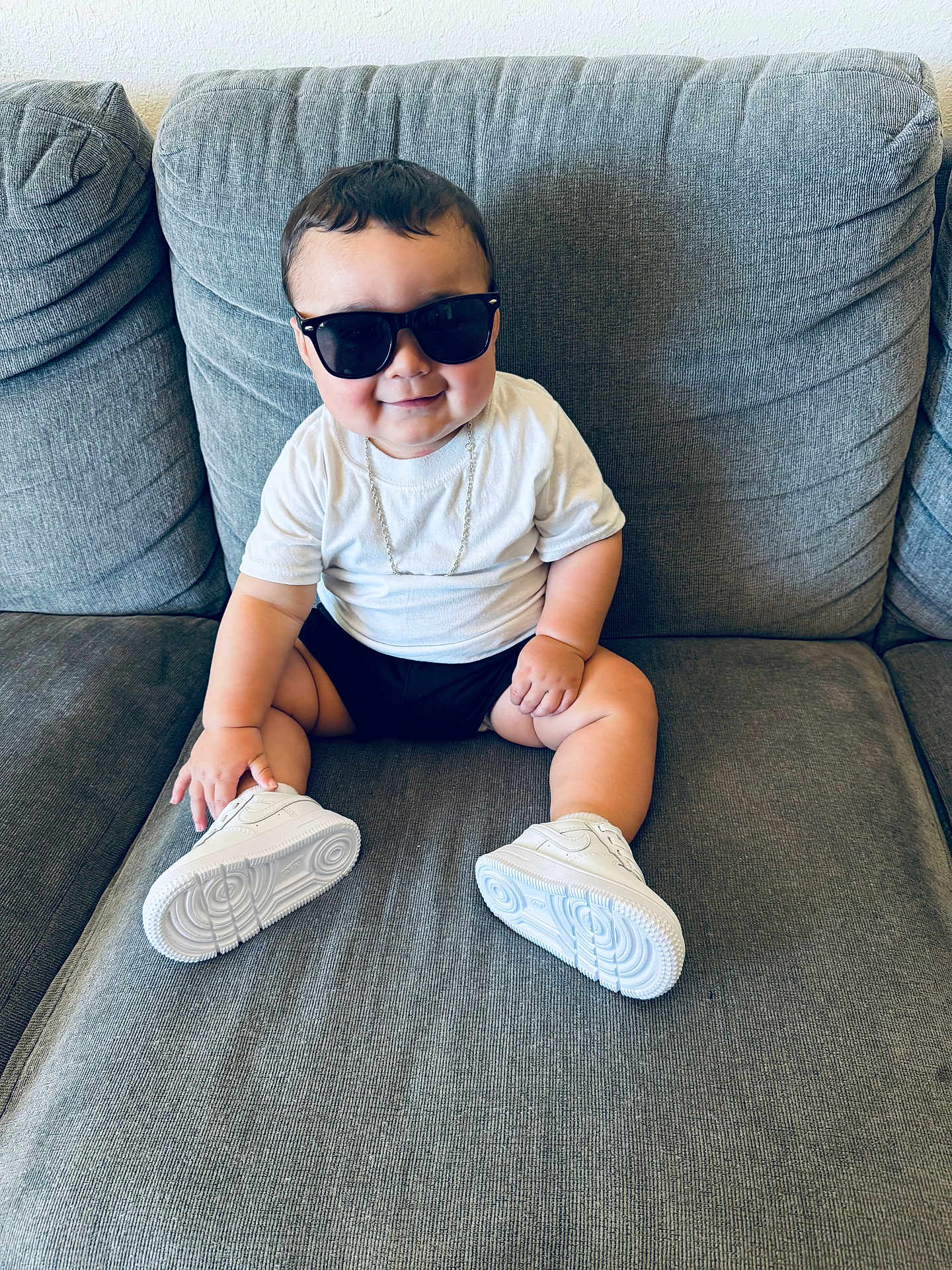 Israel joined the competition — help win amazing prizes! baby, child, sunglasses, white_tshirt, white_sneakers, smiling, couch, indoor, cute, fashion, young_child, sitting, casual, funny, portrait, person, footwear, accessory, happy, plush