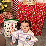 Rain is registered to the contest to win money with this photo: toddler, child, pigtails, sitting, carpet, christmas, gifts, gift_bags, holiday, indoors, playful, cute, festive, decorations, smiling, floor, young_child, person, clothing, present