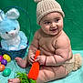 baby, basket, blue_blanket, blue_bunny, bunny_hat, child, chubby, crocheted_carrot, cute, diaper_cover, easter_eggs, green_backdrop, happy, infant, knitted_hat, plush_toy, portrait, sitting, smiling, soft_toy