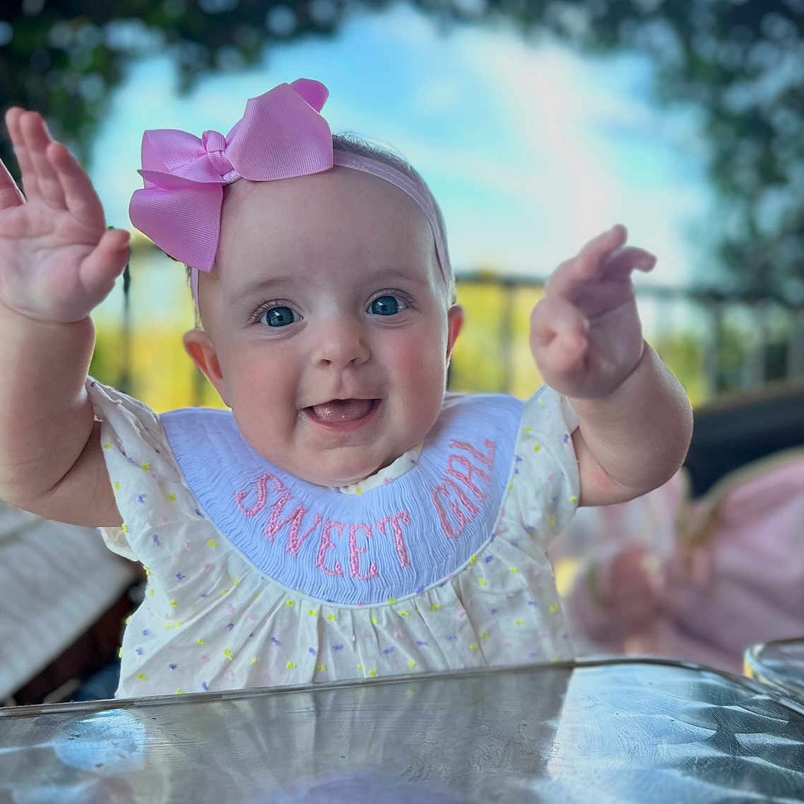 Ellie Grace joined the competition — help win amazing prizes! baby, background_blur, bib, child, closeup, clothing, cute, daylight, face, girl, hands, happy, headband, infant, outdoor, person, pink_bow, portrait, smiling, table