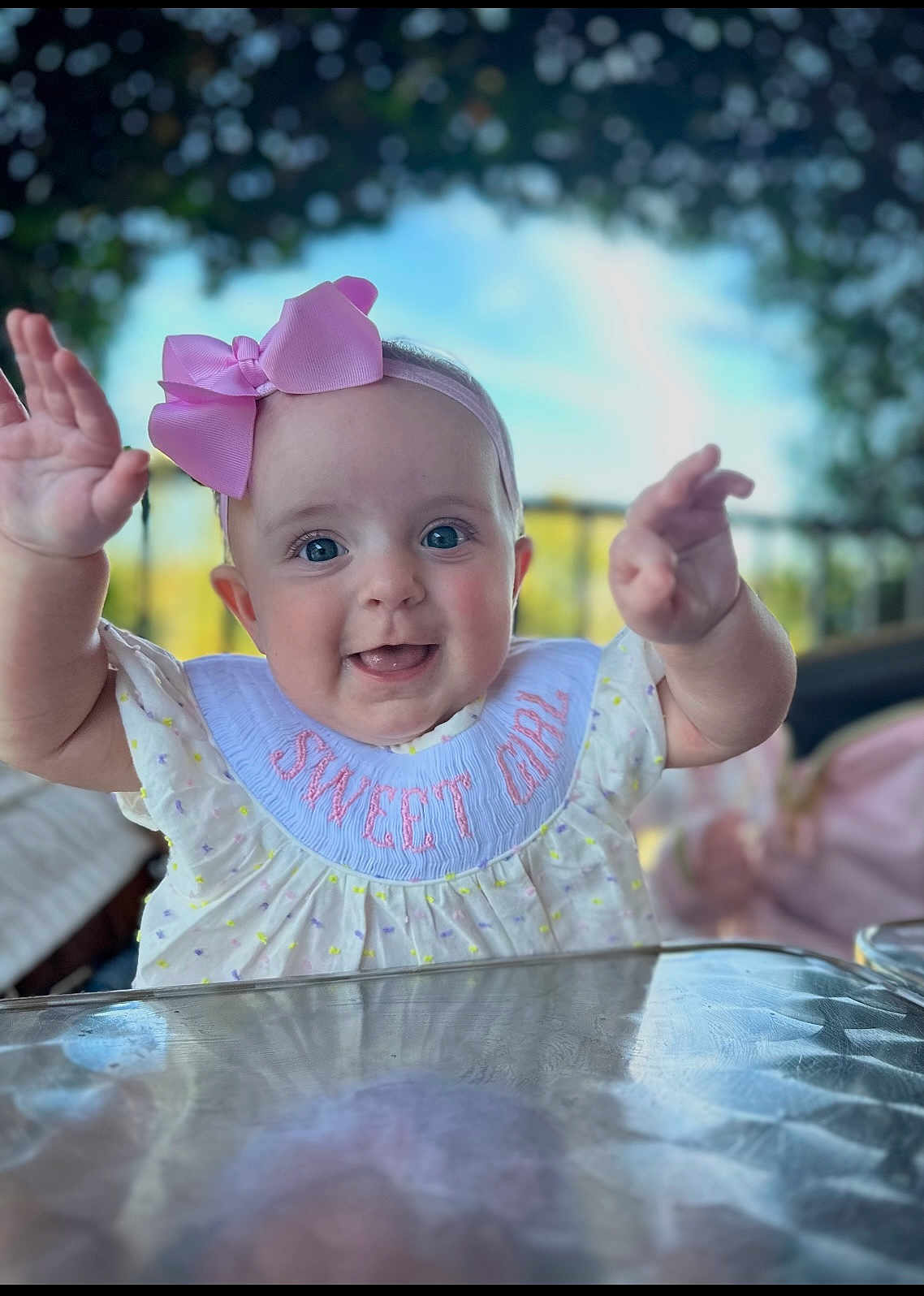 Ellie Grace joined the competition — help win amazing prizes! baby, child, girl, pink_bow, bib, smiling, happy, portrait, closeup, hands, outdoor, daylight, face, cute, infant, clothing, table, background_blur, headband, person