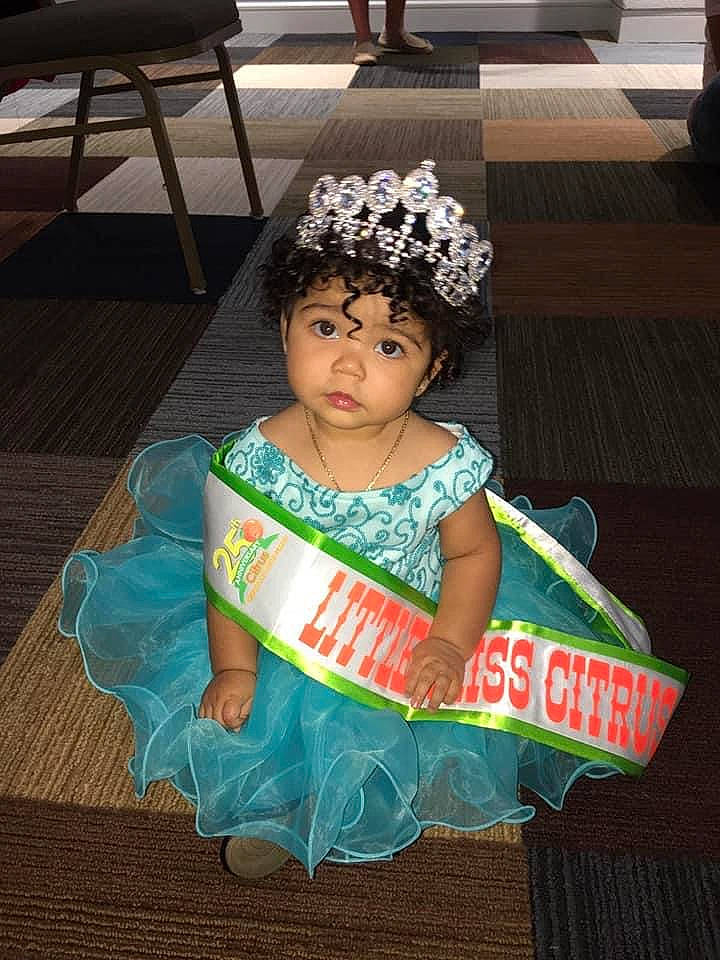 Esmeralda is registered to the contest to win money with this photo: baby_toddler_clothing, child, costume, dress, event, fashion_accessory, fashion_design, flooring, fun, hair_accessory, happy, headband, headpiece, jewellery, party, person, ruffle, sitting, toddler, tradition