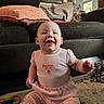 baby, child, smiling, pink_clothing, sitting, indoor, couch, toy, carpet, home, cute, happy, infant, person, furniture, floor, girl, playtime, room, portrait