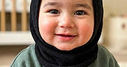 Wali Haider is registered to the contest to win money with this photo: toddler, child, smile, face, balaclava, black_headwear, green_sweater, embroidery, fox, trees, stars, moon, indoor, crib, blurred_background, rosy_cheeks, portrait, cute, cozy, happy