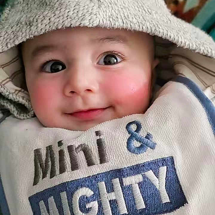Wali Haider joined the competition — help win amazing prizes! baby, child, hooded_towel, bib, smiling, face, cute, infant, portrait, indoors, person, clothing, apparel, text_on_clothing, baby_face, adorable, happy, cozy, young, closeup