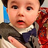 Wali Haider is registered to the contest to win money with this photo: baby, child, face, wide_eyes, vest, bow_tie, shirt, hand, tattoo, patterned_background, indoor, portrait, cute, expression, person, clothing, headwear, hat, holding, closeup