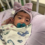 Amore is registered to the contest to win money with this photo: baby, infant, pacifier, blanket, footprints, bow_hat, striped, purple_cushion, crib_bars, sleepy, wrapped, soft, cute, indoors, portrait, child, newborn, resting, comfort, closeup