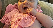 Aurelia is registered to the contest to win money with this photo: baby, pink_clothing, smiling, infant, couch, cushion, indoor, face, hand, happy, child, person, portrait, cute, young, soft_lighting, comfortable, home, relaxed, babygirl