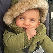 Killyan participe au concours pour gagner de l'argent avec cette photo : baby, child, hooded_jacket, green_jacket, smiling, stroller, blanket, fur_hood, cute, outdoor, happy, portrait, infant, cold_weather, warm_clothing, baby_hand, blue_eyes, closeup, face, person