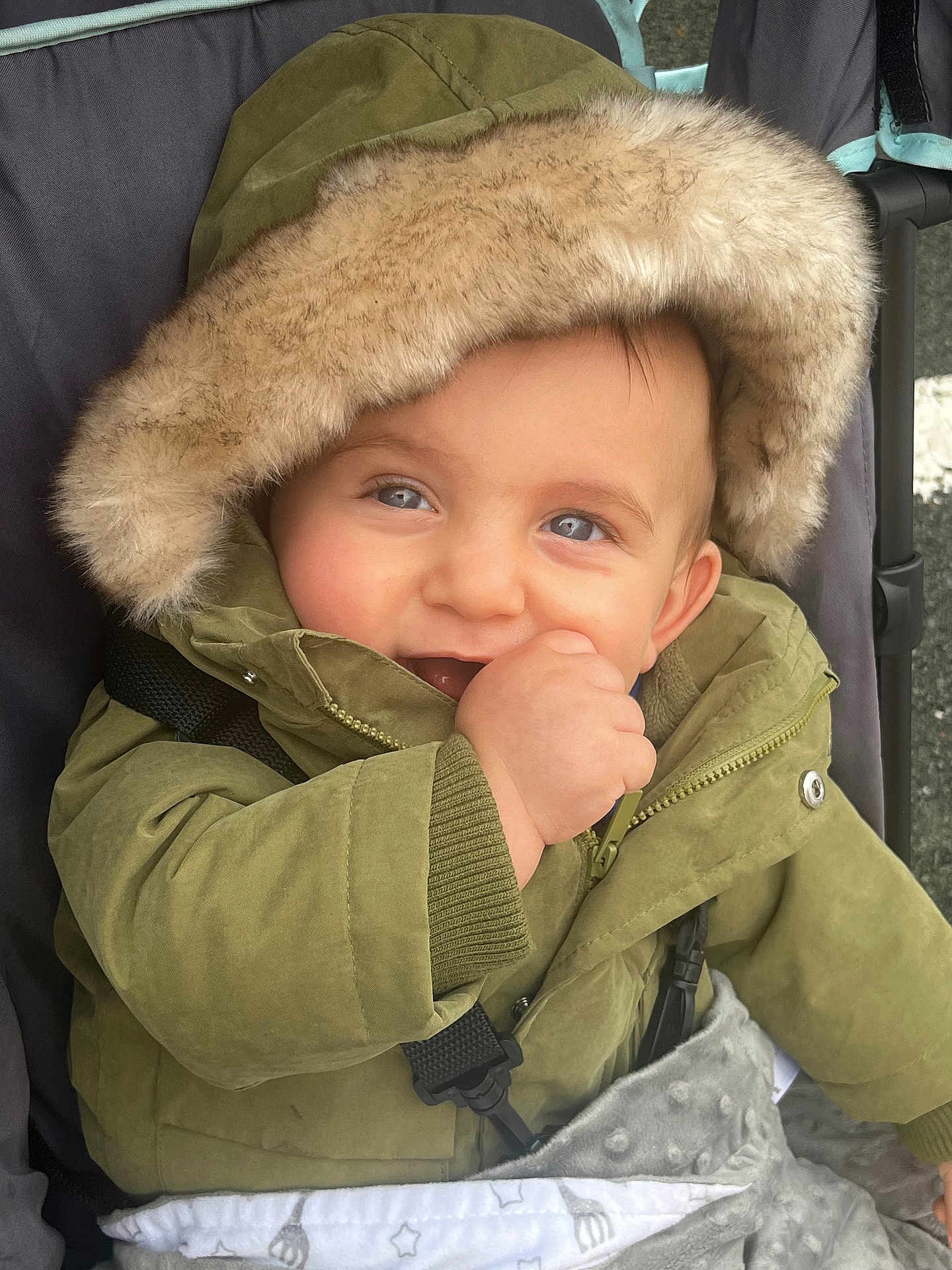 Killyan participe au concours pour gagner de l'argent avec cette photo : baby, child, hooded_jacket, green_jacket, smiling, stroller, blanket, fur_hood, cute, outdoor, happy, portrait, infant, cold_weather, warm_clothing, baby_hand, blue_eyes, closeup, face, person