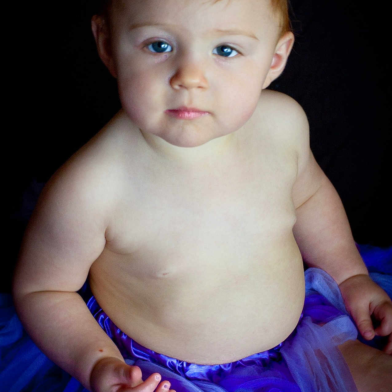 Rylie joined the competition — help win amazing prizes! baby, bare_chest, blue_eyes, child, chubby_cheeks, curious, cute, dress, expression, flower_headband, hands, headband, indoors, portrait, purple_tutu, sitting, skin, soft_lighting, toddler, young_child