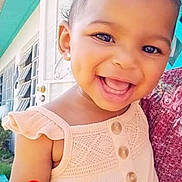 Light is registered to the contest to win money with this photo: toddler, smiling, child, dress, earrings, door, window, heart_emoji, outdoor, happy, face, person, curly_hair, buttoned_clothing, closeup, sunlight, home, wall, portrait, cute