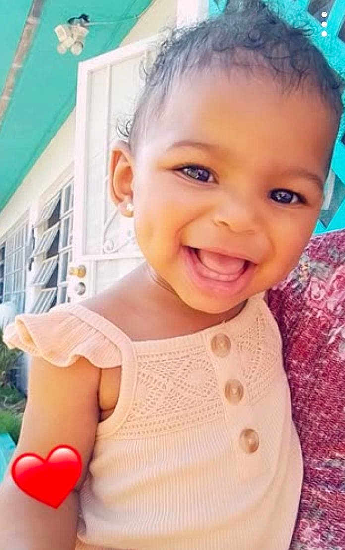 Light is registered to the contest to win money with this photo: toddler, smiling, child, dress, earrings, door, window, heart_emoji, outdoor, happy, face, person, curly_hair, buttoned_clothing, closeup, sunlight, home, wall, portrait, cute