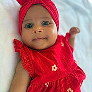 Lisa a rejoint le concours — aidez-le/la à gagner de superbes lots ! baby, infant, child, red_dress, headwrap, smile, face, eyes, arm, lying_down, soft_surface, cute, portrait, closeup, apparel, fabric, flower_pattern, skin, happy, indoors