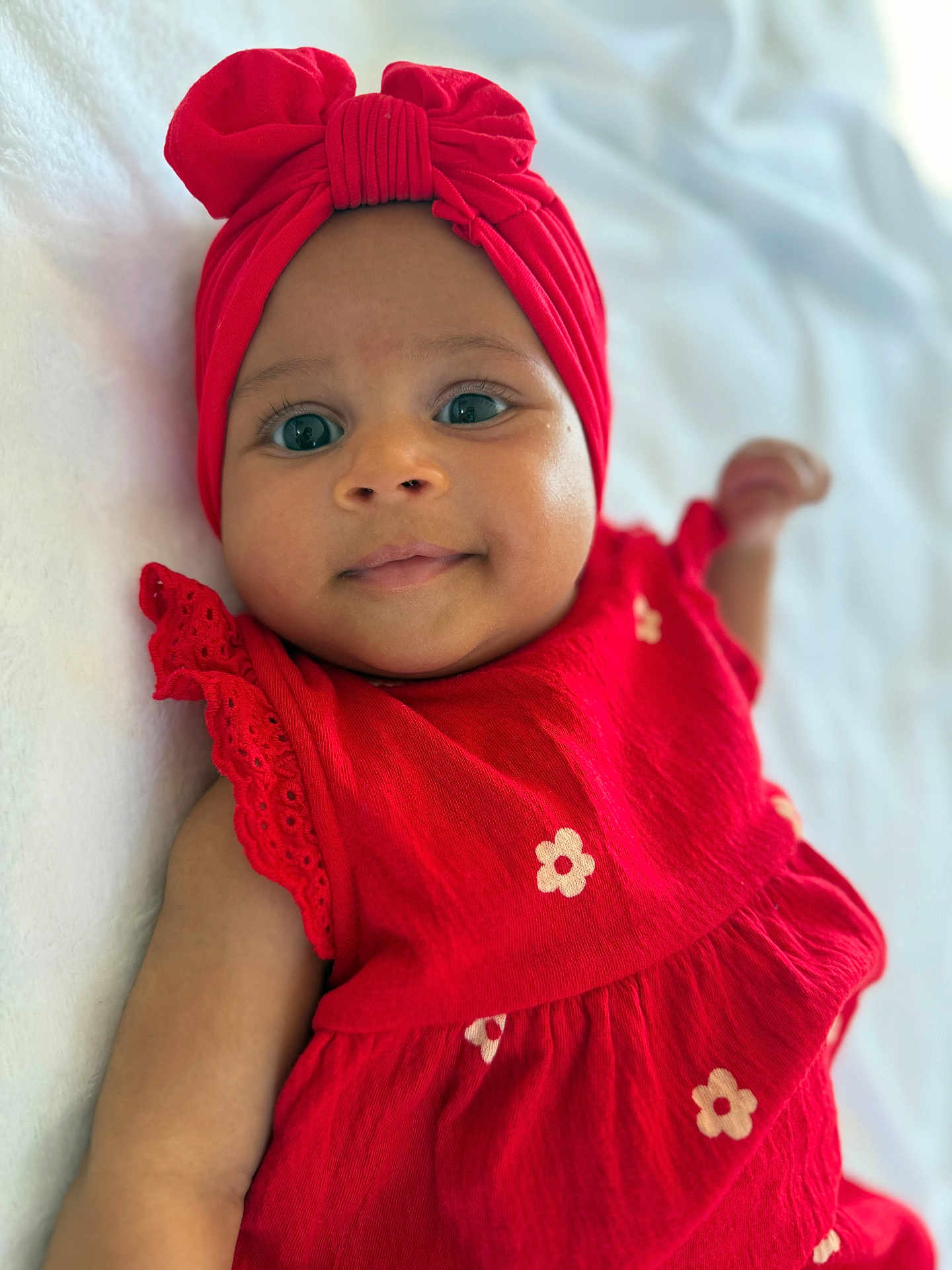 Lisa a rejoint le concours — aidez-le/la à gagner de superbes lots ! baby, infant, child, red_dress, headwrap, smile, face, eyes, arm, lying_down, soft_surface, cute, portrait, closeup, apparel, fabric, flower_pattern, skin, happy, indoors