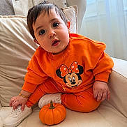 Amelia joined the competition — help win amazing prizes! baby, child, infant, portrait, sitting, orange_outfit, minnie_mouse, pumpkin, sneaker, couch, cushions, window, indoor, daylight, wide_eyed, surprised, jewelry, bracelet, cross_necklace, autumn