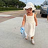 toddler, child, girl, white_dress, sunhat, stuffed_toy, purse, sidewalk, parking_lot, car, sandals, outdoor, walking, summer, cute, young_child, person, accessory, toy, daytime