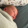 newborn, baby, blanket, pillow, floral_pattern, face, head, infant, lying_down, soft_texture, indoor, closeup, cute, child, person, sleeping_area, resting, wrapped, calm, cozy