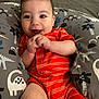 Alexander joined the competition — help win amazing prizes! baby, infant, smile, happy, onesie, orange_clothing, striped_clothing, dinosaur_pattern, pillow, bed, indoor, cute, child, person, hands, face, skin, head, young, expression