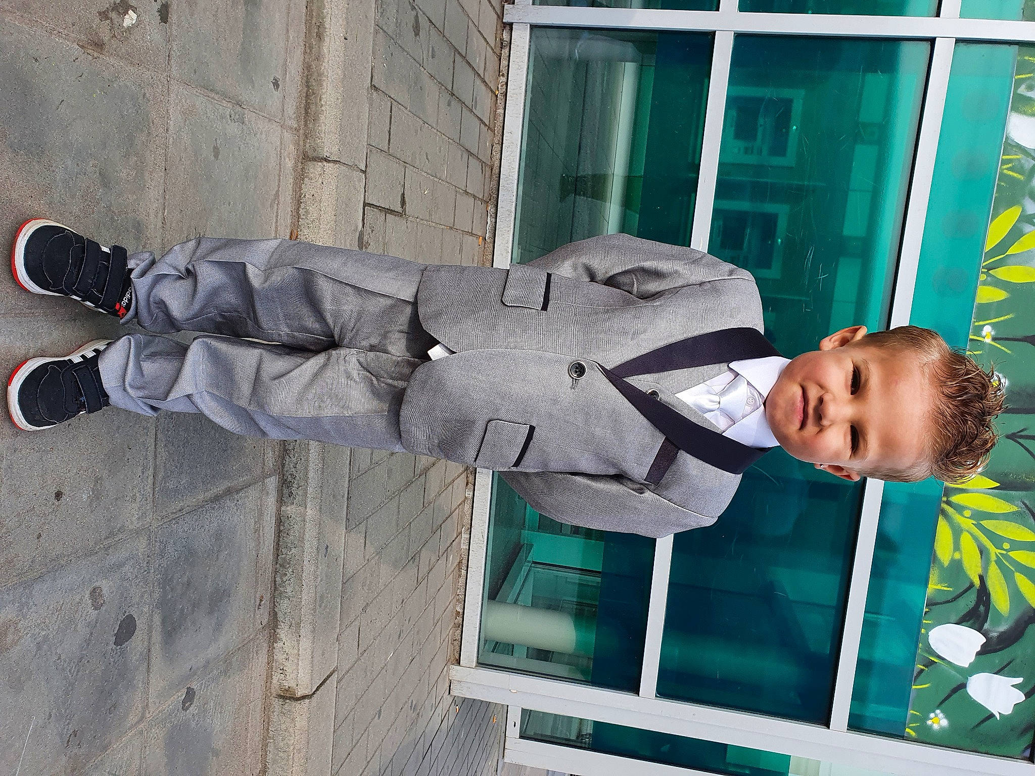 Yohan a rejoint le concours — aidez-le/la à gagner de superbes lots ! baby_toddler_clothing, concrete, cross_training_shoe, flooring, green, hat, human_leg, joy, outdoor_shoe, person, personal_protective_equipment, shoe, sleeve, smile, sneakers, street_fashion, toddler, walking_shoe, window