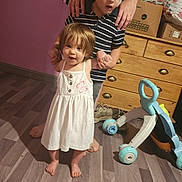Kayla a rejoint le concours — aidez-le/la à gagner de superbes lots ! child, toddler, indoor, wooden_floor, dresser, toy, baby_dress, barefoot, person, supporting_hands, striped_shirt, flooring, home, family, playtime, young_children, childhood, cute, smiling, learning_to_walk