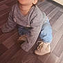 toddler, child, crawling, gray_sweater, flower_detail, blue_jeans, beige_boots, wooden_floor, indoor, couch, happy, smiling, person, hair_tied, cute, cozy, young_child, flooring, home, casual_clothing