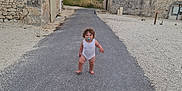 Lucyan a rejoint le concours — aidez-le/la à gagner de superbes lots ! toddler, child, pacifier, curly_hair, road, rural, stone_building, sunset, sky, barefoot, walking, outdoor, nature, vintage, countryside, pathway, person, small_child, alone, exploration