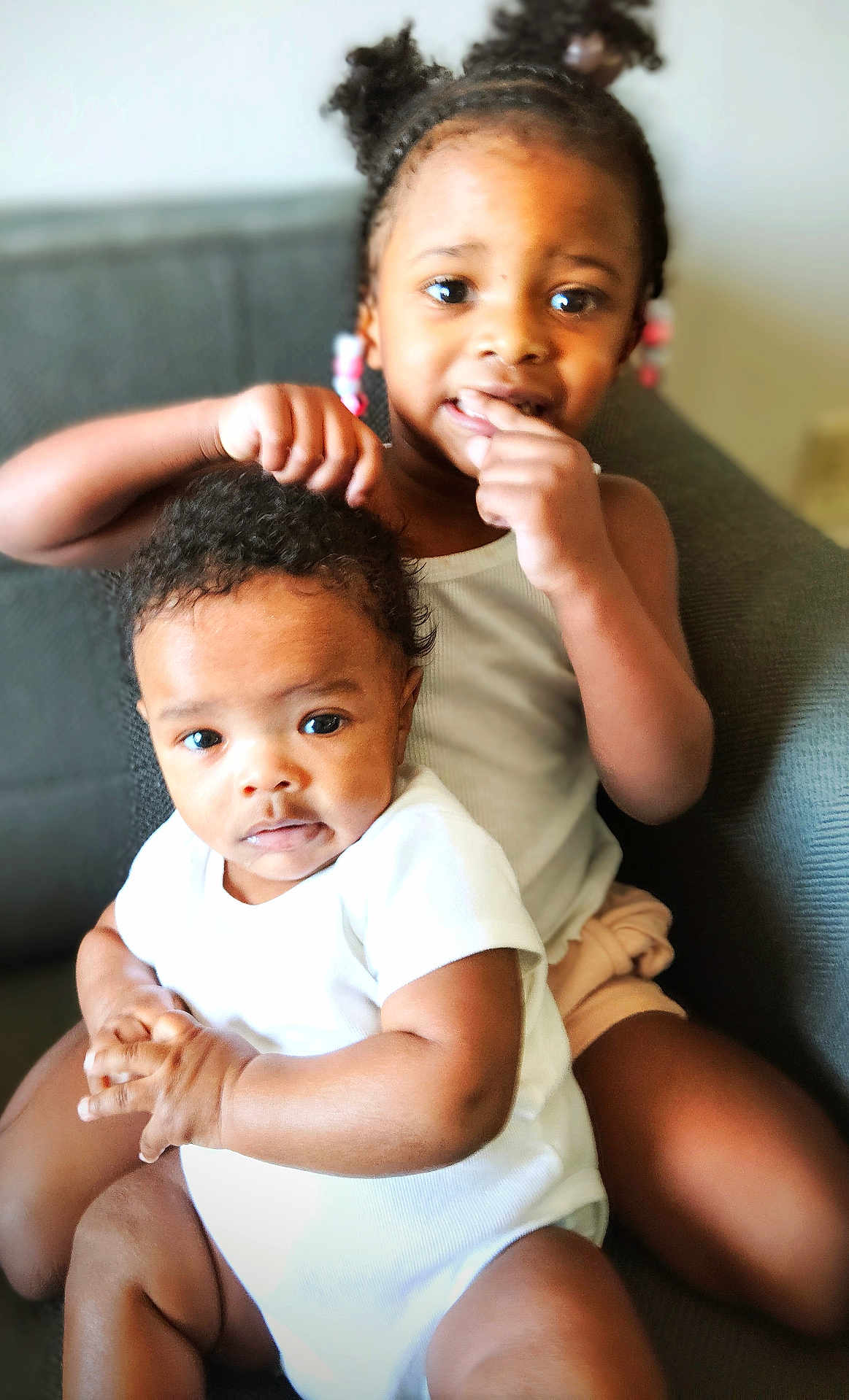 Jeremiah Folks is registered to the contest to win money with this photo: child, baby, sibling, couch, indoor, curly_hair, white_clothing, playful, cute, family, toddler, smiling, portrait, person, home, young_child, black_hair, casual, seated, interaction