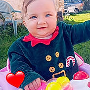 Lylyana participe au concours pour gagner de l'argent avec cette photo : baby, child, blue_eyes, smiling, outdoor, grass, walker, toy, pink, red_heart, festive_clothing, button_details, stone_wall, green_chair, sunny, daylight, happy, play, person, closeup