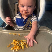 Leonardo is registered to the contest to win money with this photo: toddler, child, high_chair, food, spaghetti, messy, face, smile, meal, indoor, baby, clothing, tray, hand, seat_belt, expression, cute, portrait, feeding, playful