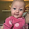 Amelia joined the competition — help win amazing prizes! baby, infant, pink_clothing, polka_dots, face, eyes, smile, indoor, tattoo, arm, hand, wall, shelf, clock, person, cute, portrait, child, home, cozy