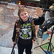 Brantlee Arthur Allen is registered to the contest to win money with this photo: axe, backdrop, big_brother, black_shirt, boy, camouflage, child, clouds, floor, garage, indoor, lighting, person, playful, shoes, smiling, stars, toy, vest, waving