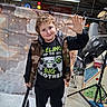 axe, backdrop, big_brother, black_shirt, boy, camouflage, child, clouds, floor, garage, indoor, lighting, person, playful, shoes, smiling, stars, toy, vest, waving