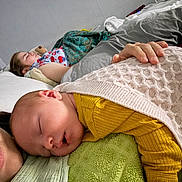 Kai is registered to the contest to win money with this photo: baby, child, sleeping, blanket, bed, pillow, hand, teddy_bear, yellow_clothing, rest, cozy, indoor, person, face, peaceful, nap, soft_texture, comfort, family, home