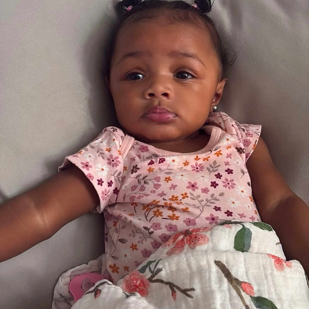 Mayci joined the competition — help win amazing prizes! baby, blanket, child, clothing, comfort, couch, cute, earrings, expression, face, floral, girl, indoor, infant, person, pigtails, portrait, relaxing, skin, soft