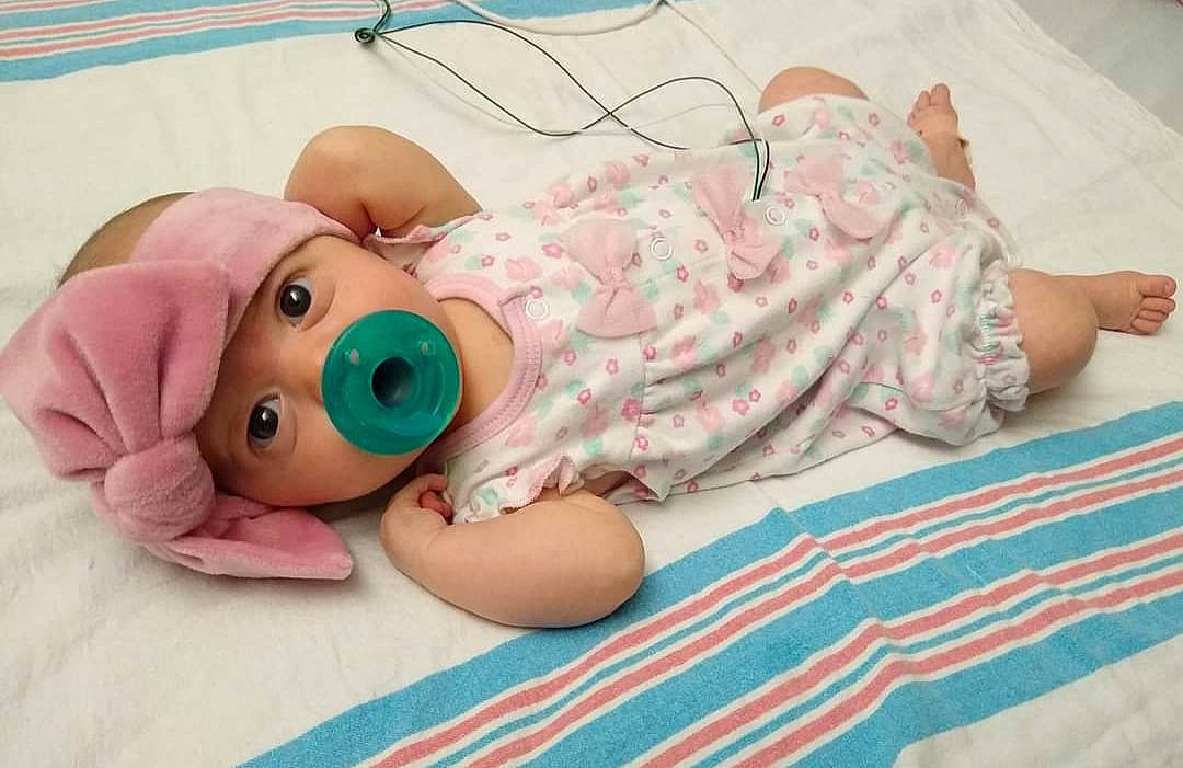 Cadence is registered to the contest to win money with this photo: baby, baby_products, baby_safety, baby_toddler_clothing, baby_toys, bed, bedding, cheek, child, comfort, headwear, linens, pattern, person, pink, room, service, skin, textile, toddler