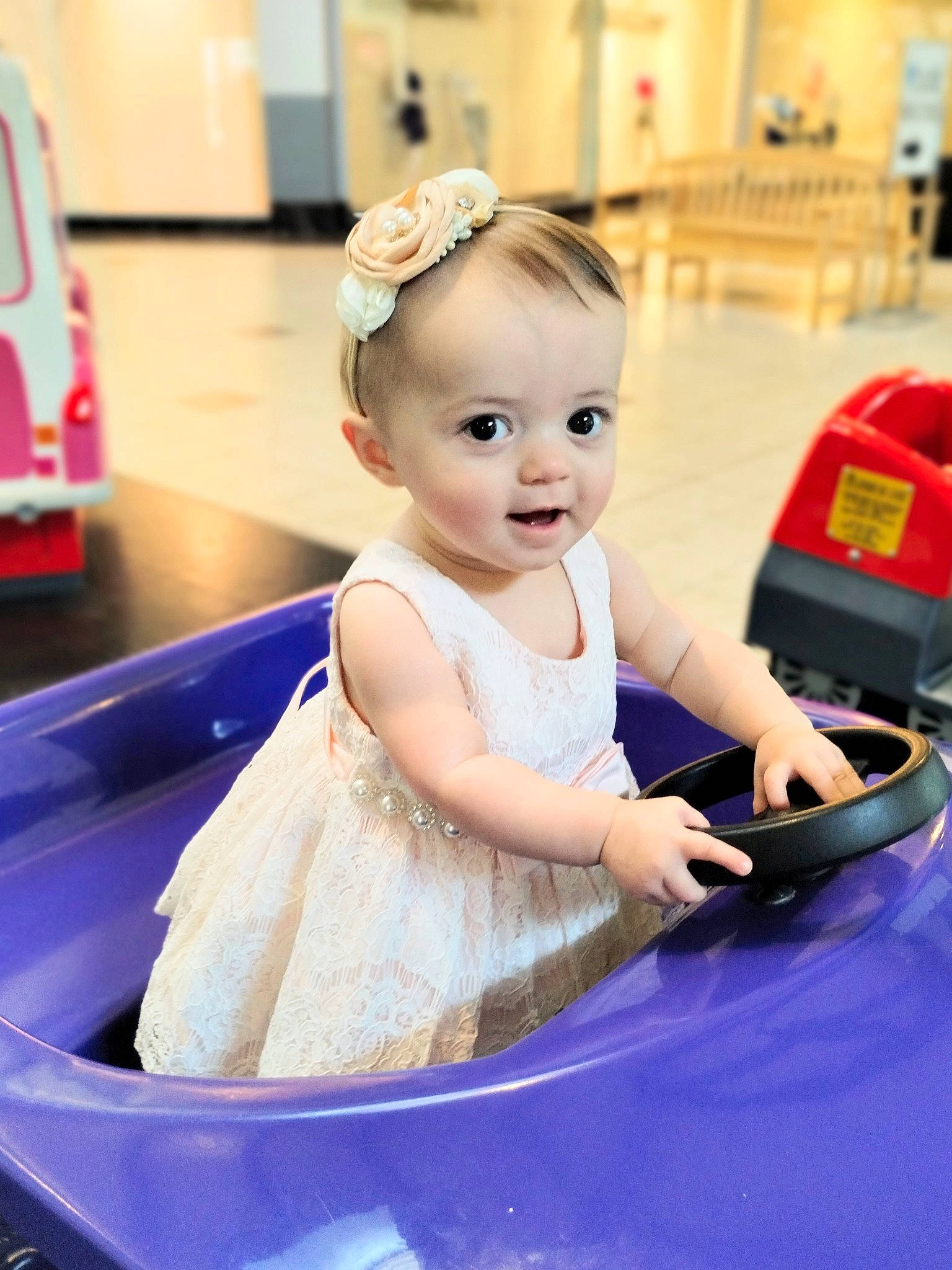 Cadence is registered to the contest to win money with this photo: baby, baby_toddler_clothing, child, dress, event, flooring, fun, happy, leisure, person, recreation, room, sitting, skin, smile, standing, toddler
