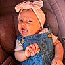 baby, infant, headband, bow, denim_overalls, car_seat, smiling, happy, cute, child, clothing, person, portrait, skin, hand, face, baby_fashion, indoor, seat, expression