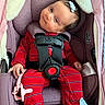 baby, car_seat, graco, pajamas, red_clothing, striped_clothing, pacifier, pink_pacifier, infant, child, face, head, hair_bow, socks, mouse_design, seat_belt, safety_harness, hand, portrait, indoor