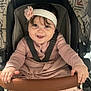 baby, child, smiling, stroller, headband, flower, pink, blanket, clothing, seatbelt, hands, infant, cute, portrait, indoors, happy, person, baby_girl, cushion, fabric