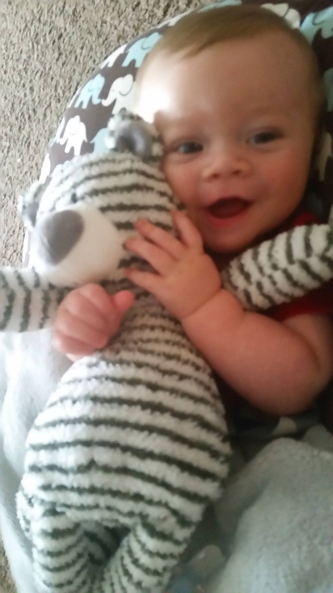 Tate is registered to the contest to win money with this photo: arm, baby, baby_toddler_clothing, comfort, eye, face, facial_expression, hand, head, human_body, iris, mammal, nose, organ, person, photograph, skin, smile, textile, vertebrate